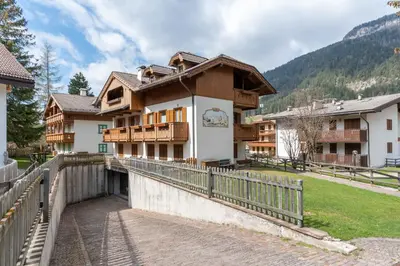 a house in the mountains with a wooden fence at Casa Sartori in Pozza di Fassa