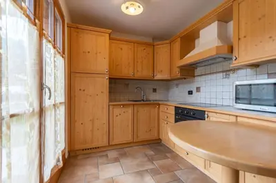 a kitchen with wooden cabinets and a sink at Casa De La Veisc in Pozza di Fassa