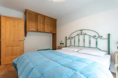a bedroom with a large blue bed with wooden cabinets at Casa De La Veisc in Pozza di Fassa