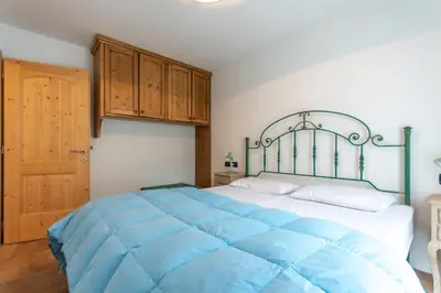 a bedroom with a large blue bed with wooden cabinets at Casa De La Veisc in Pozza di Fassa