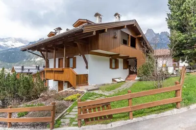 a house on top of a hill with a fence at Casa Fave' in Pozza di Fassa
