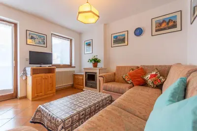 a living room with a couch and a tv at Casa Fave' in Pozza di Fassa