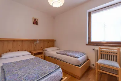 a bedroom with two beds and a window at Casa Fave' in Pozza di Fassa