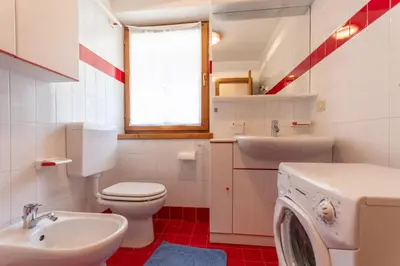 a bathroom with a toilet sink and a washing machine at Casa Fave' in Pozza di Fassa