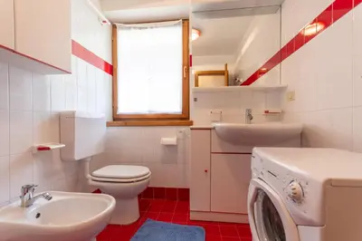 a bathroom with a toilet sink and a washing machine at Casa Fave' in Pozza di Fassa