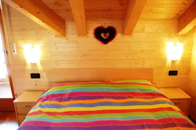 a bedroom with a bed with a heart on the wall at Chalet alla Cascata in Badia