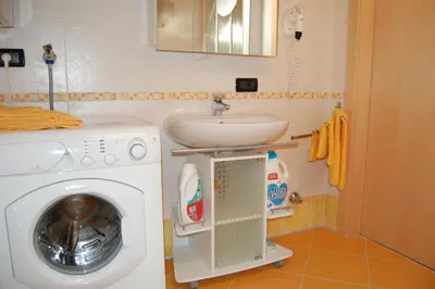 a bathroom with a washing machine and a sink at Chalet alla Cascata in Badia