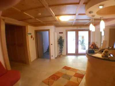 a living room with wooden ceilings and a hallway at Garni Manuela in Cavalese