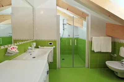 a green bathroom with a sink and a shower at Garni Manuela in Cavalese