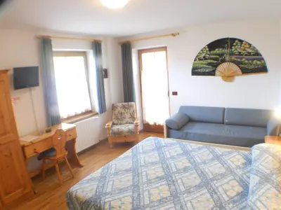 a bedroom with a bed and a couch and a chair at Garni Manuela in Cavalese