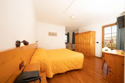 a bedroom with a bed with a yellow bedspread at Garni Manuela in Cavalese