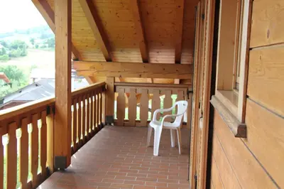 a wooden porch with a white chair on it at Garnì Goccia d'Oro in Cavalese