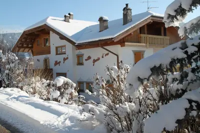 a house covered in snow in front at Garnì Goccia d'Oro in Cavalese