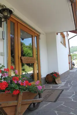 a building with flowers in front of a window at Garnì Goccia d'Oro in Cavalese