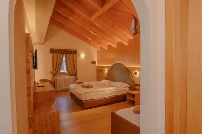 a large room with two beds and a table at Hotel Tita Piaz in Canazei