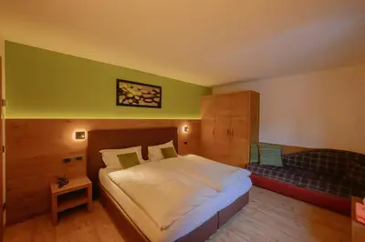 a bedroom with a bed and a bench in it at Hotel Tita Piaz in Canazei