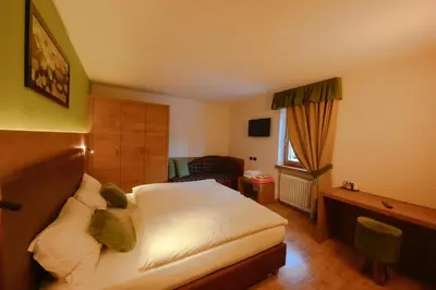 a hotel room with a bed and a chair at Hotel Tita Piaz in Canazei