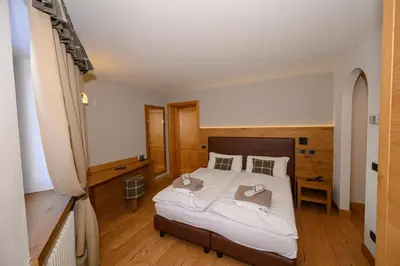 a bedroom with a large bed with white sheets and pillows at Hotel Tita Piaz in Canazei
