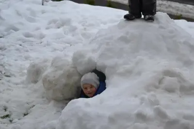 a child is poking his head out of a snow pile at Gruberhof in Rodengo