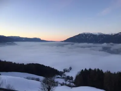 a view of a snow covered mountain with a foggy valley at Gruberhof in Rodengo