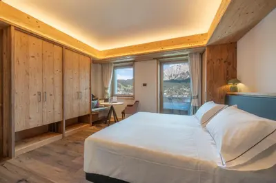 a bedroom with a large bed and a large window at Villa Oretta in Cortina dʼAmpezzo