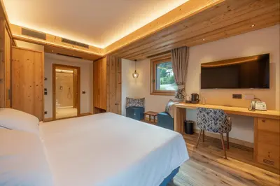 a bedroom with a bed and a desk with a television at Villa Oretta in Cortina dʼAmpezzo