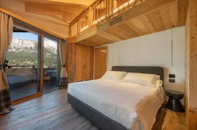a bedroom with a bed and a large window at Villa Oretta in Cortina dʼAmpezzo
