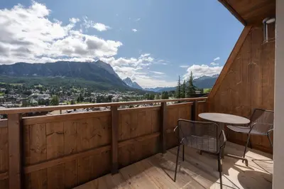a balcony with a table and chairs and mountains at Villa Oretta in Cortina dʼAmpezzo