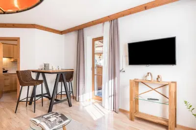 a living room with a table and a television on a wall at Sonnenresidenz Kastelruth in Castelrotto