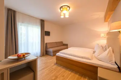a hotel room with a bed and a couch at Tirolerin Garni Hotel in Termeno