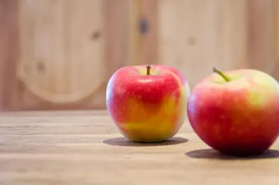two apples sitting on top of a wooden table at Tirolerin Garni Hotel in Termeno