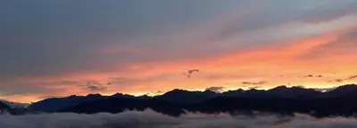 a sunset over the mountains with a layer of clouds at Hotel Waldheim in Sarnonico