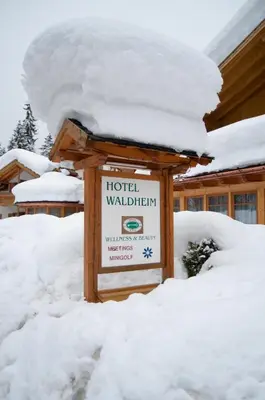 a sign in the snow in front of a lodge at Hotel Waldheim in Sarnonico