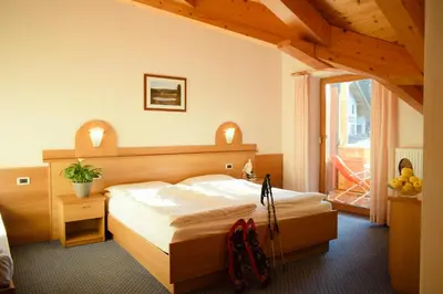 a bedroom with a bed with a wooden headboard at Hotel Waldheim in Sarnonico