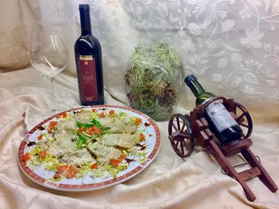 a table with a plate of food and a bottle of wine at Hotel Waldheim in Sarnonico
