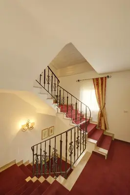 a spiral staircase in a house with red carpet at Hotel Garni Hubertus in Tirolo