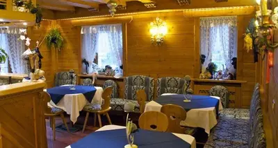a restaurant with white couches and tables and lights at Albergo Genziana in San Vigilio Di Marebbe