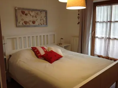 a white bed with two red pillows on it at VILLA ROOMS in Laives