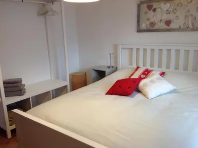 a white bed with two red pillows on it at VILLA ROOMS in Laives