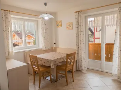 a dining room with a table and chairs and windows at Casa Soraruf in Campitello di Fassa