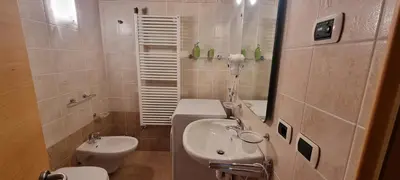 a bathroom with a sink and a toilet and a mirror at Casa Soraruf in Campitello di Fassa