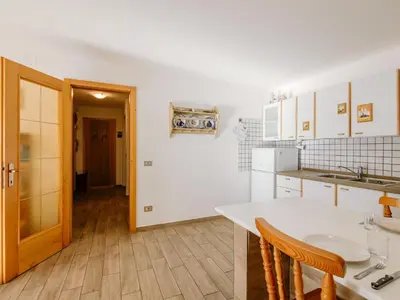 a kitchen with white cabinets and a table and chairs at Apartment Cesa Lucilla by Interhome in Canazei