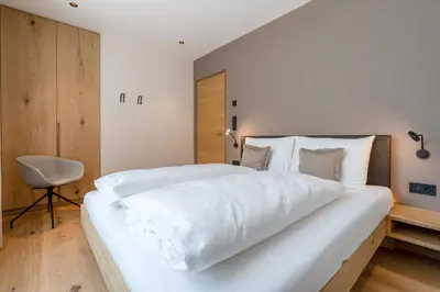 a large white bed in a room with a chair at Feldhof Vilpian- Urlaub auf dem Bauernhof in Vilpiano