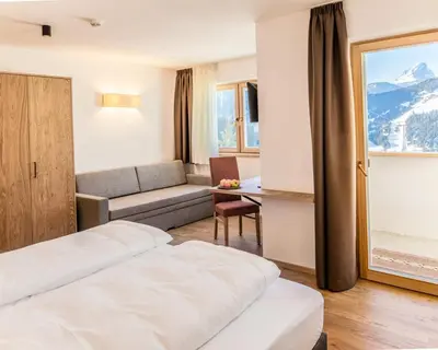 a hotel room with two beds and a couch at Garni B&B Chi Vai in San Vigilio Di Marebbe