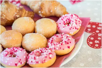 a plate of donuts with pink frosting and sprinkles at Garni B&B Chi Vai in San Vigilio Di Marebbe