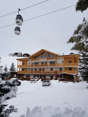 a large building with a car parked in the snow at Garni B&B Chi Vai in San Vigilio Di Marebbe