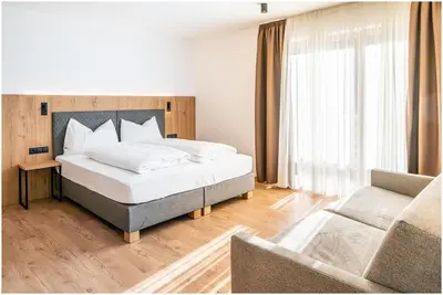 a bedroom with a large bed and a couch at Garni B&B Chi Vai in San Vigilio Di Marebbe