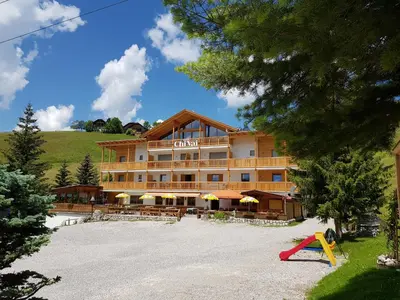 a large hotel with a playground in front of it at Garni B&B Chi Vai in San Vigilio Di Marebbe