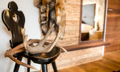 a black chair with antlers on it next to a mirror at Garni Residence Soraiser in Selva di Val Gardena
