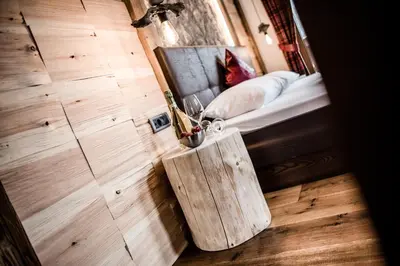a bedroom with a bed with a wooden floor and a table at Garni Residence Soraiser in Selva di Val Gardena
